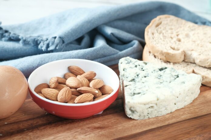 Photo by Towfiqu barbhuiya a bowl of almonds, bread, and an egg on a cutting board