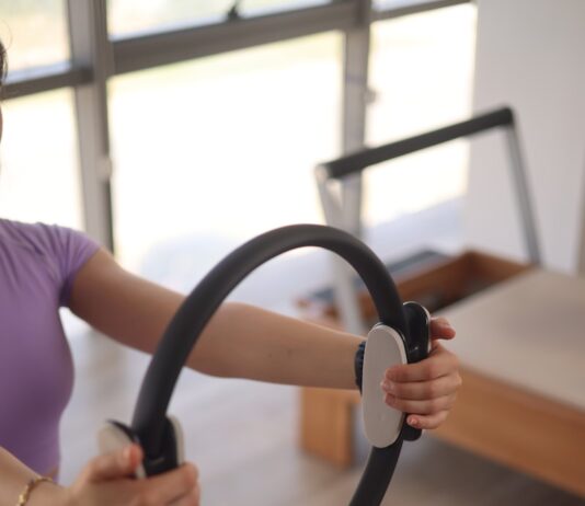 필라테스의 과학적 근거와 신체에 미치는 영향 a woman sitting on the floor holding a steering wheel