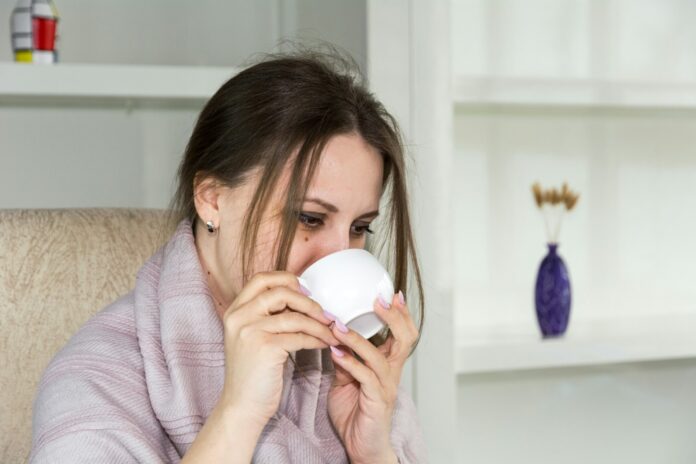 Photo by Bermix Studio a woman sitting in a chair drinking from a cup