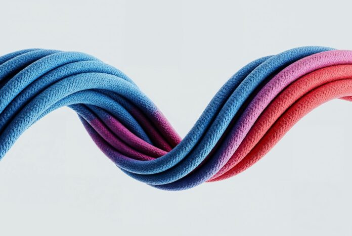 Photo by Maxim Berg Colorful, wavy cables intertwine against a white background.