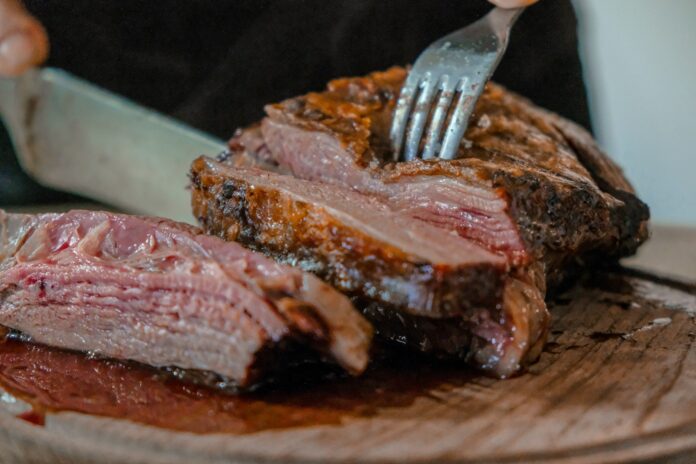 Photo by José Ignacio Pompé person slicing a meat on brown wooden board