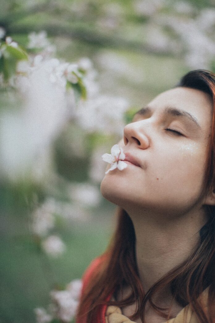Photo by Elina Sazonova a woman with her eyes closed and a flower in her mouth
