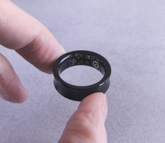 AI 기반 건강 관리, 개인 맞춤형 솔루션으로 헬스케어의 미래를 연다 Fingers hold a black smart ring with circuits visible.