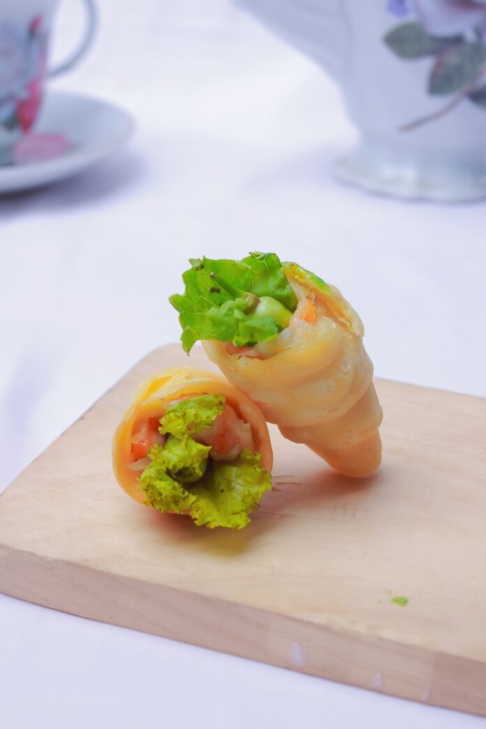 a wooden cutting board topped with a vegetable roll